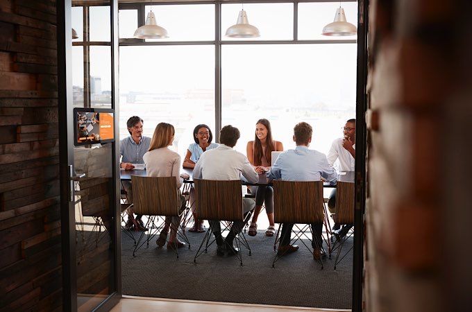 Team in a boardroom meeting seen through open doors, full length